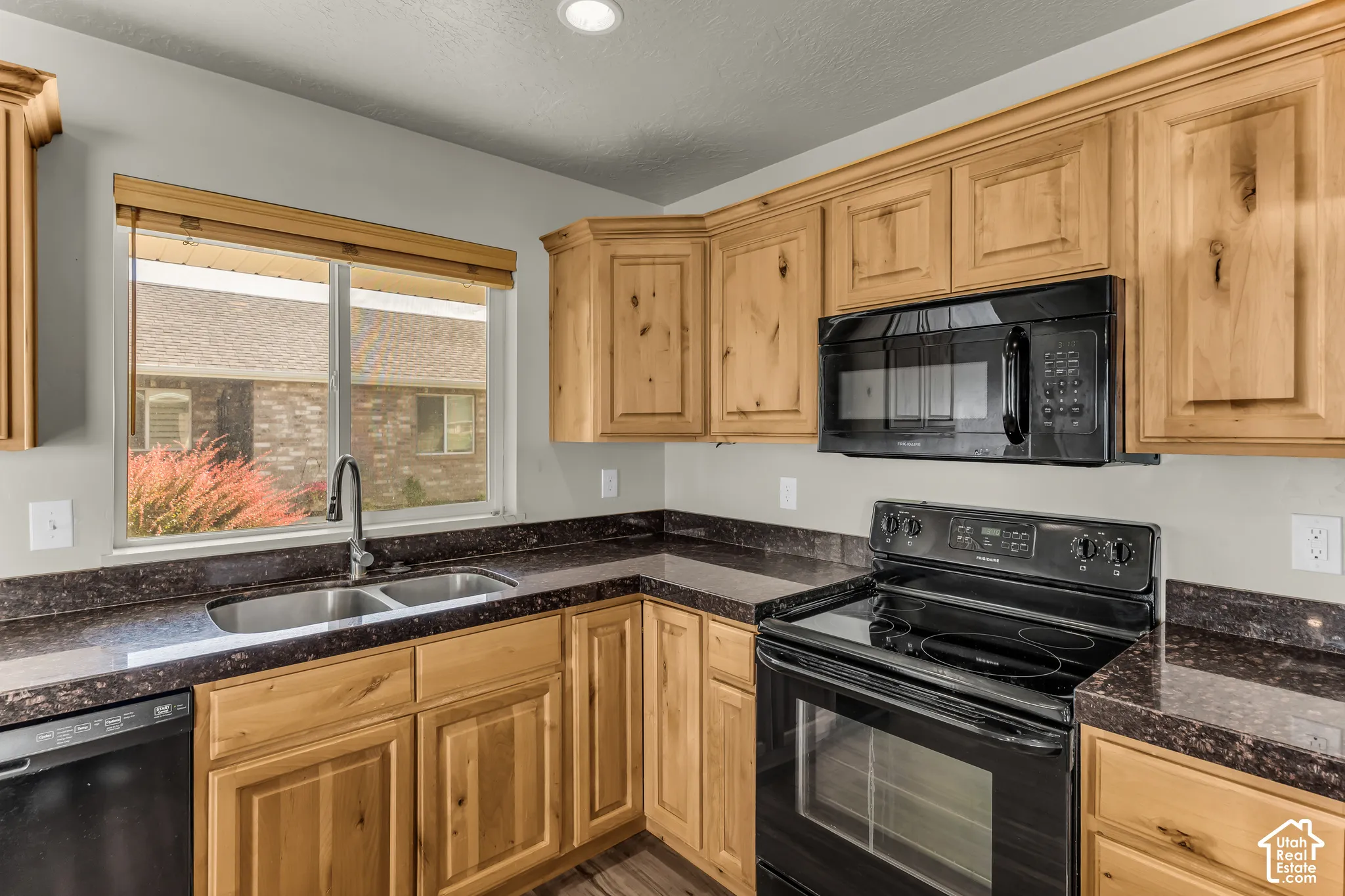 Kitchen featuring wood cabinetry, dark countertops, and black appliances