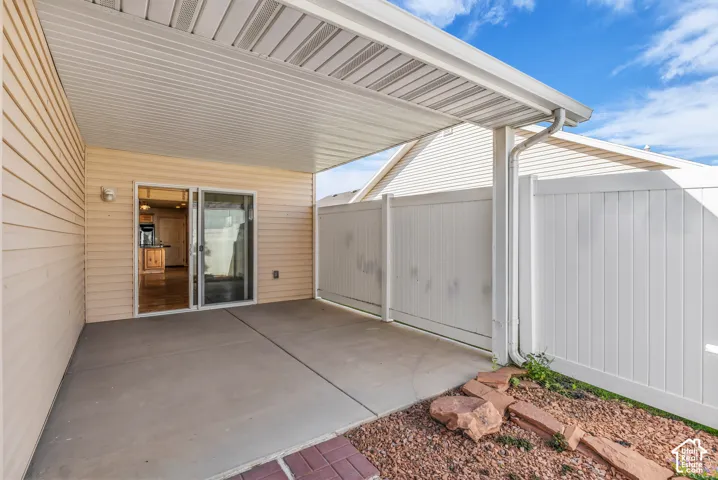 Covered patio with concrete flooring, sliding glass door entry, and privacy fencing