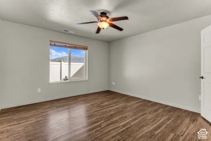 Wood-finish flooring, ceiling fan with integrated lighting, a spacious window with blinds, and white interior door