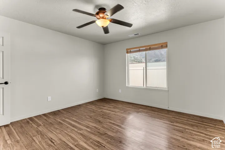 Wood-finish flooring, ceiling fan with integrated lighting, and a single window with mountain scenery