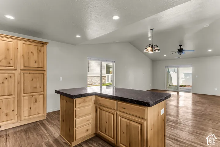 Wood-finish flooring throughout, vaulted ceiling, recessed lighting, wood cabinetry, and sliding glass door
