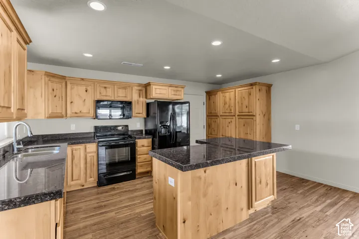 Kitchen featuring a central island with countertop seating, wood-finish flooring, recessed lighting, and ample cabinetry