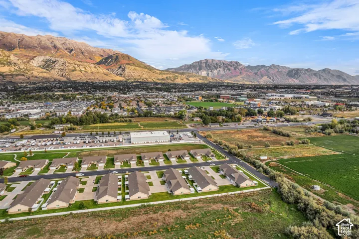 Residential development with uniform building designs, surrounded by expansive natural and cultivated green spaces, set against a distant mountain range