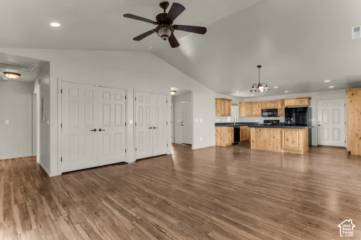 Open-concept living space featuring vaulted ceilings, wood-finish flooring, and recessed lighting
