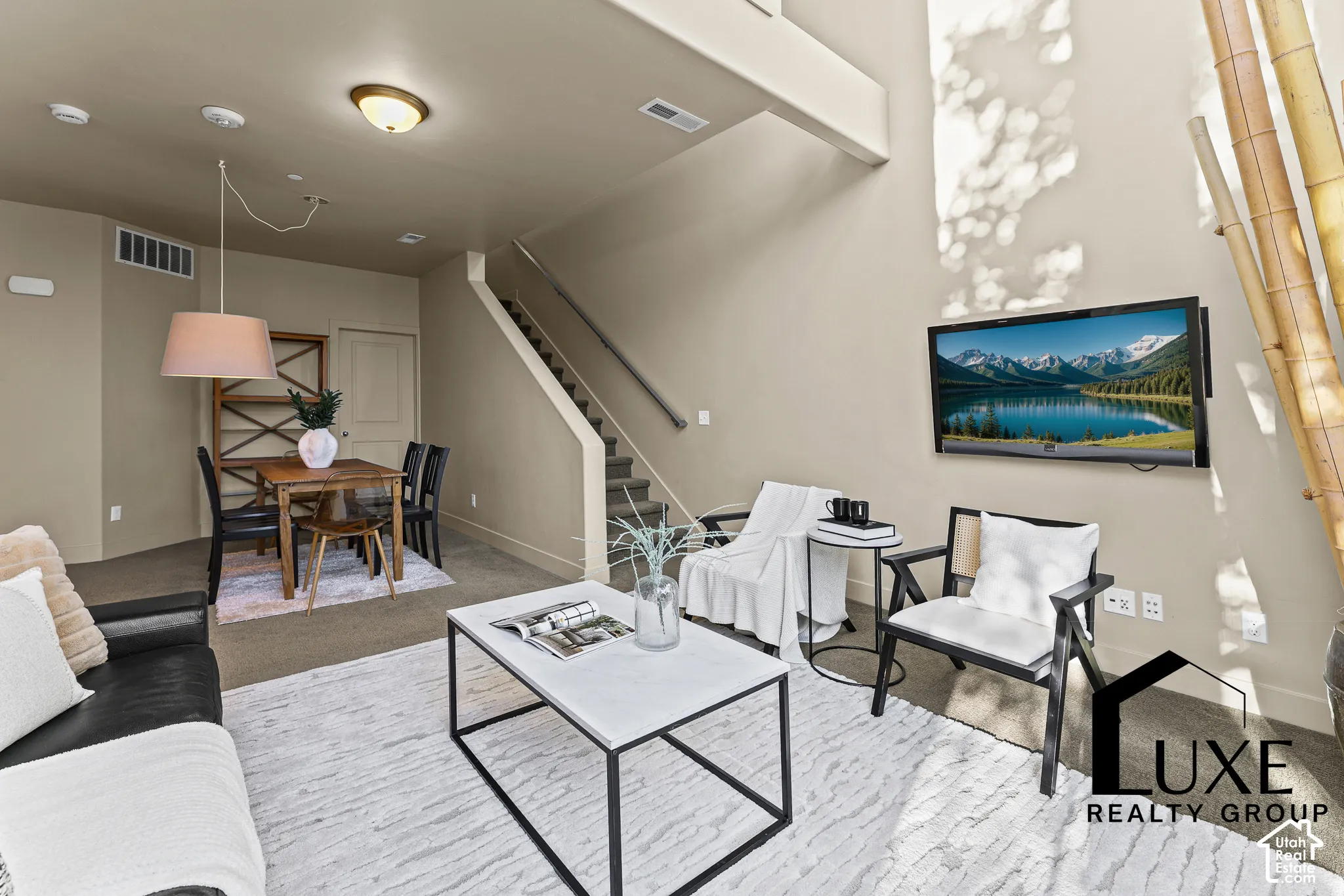 Vaulted ceiling, recessed lighting, wall-mounted television, wood-finish dining table, and staircase with metal railing