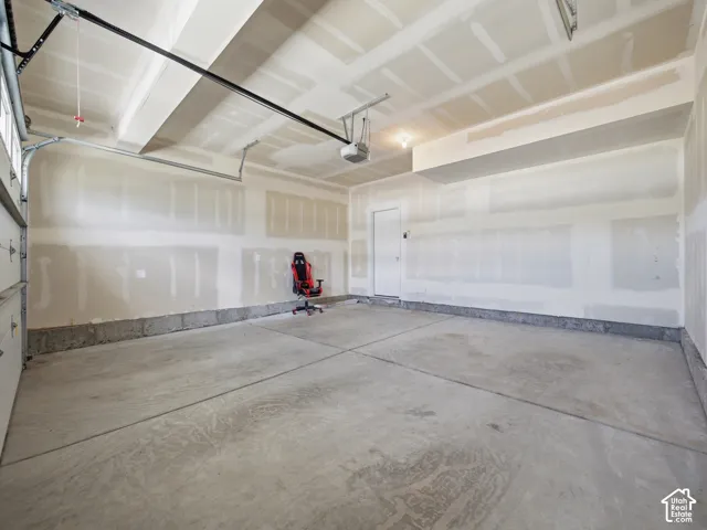 Spacious garage featuring a concrete floor, overhead door, and direct access door
