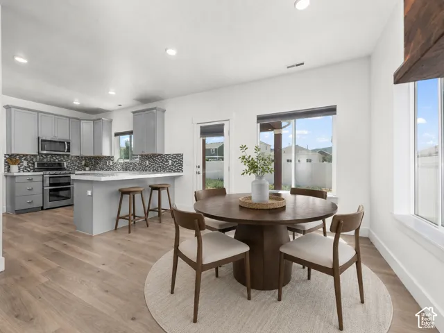 Open-concept kitchen and dining area featuring light-toned wood-finish flooring, recessed lighting, and large windows