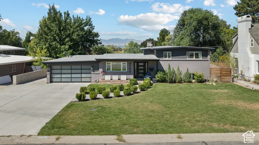 Modern mid-century residence showcasing a sleek horizontal garage with glass-panel doors, clean-lined architectural detailing, and a flat roofline