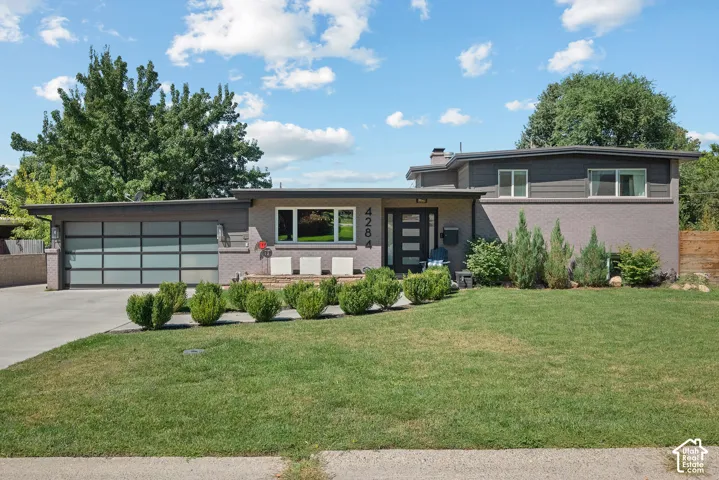 Contemporary exterior with a flat roofline, brick and siding facade, modern garage door, and a well-maintained lawn