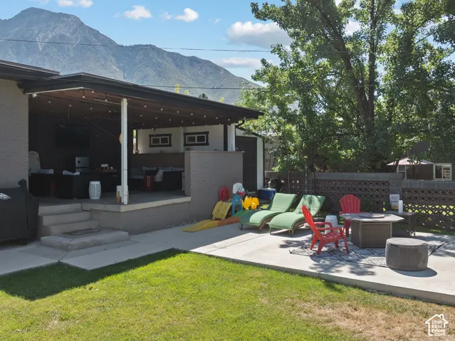 Expansive outdoor living area featuring a covered patio, concrete patio extension, and a decorative block fence