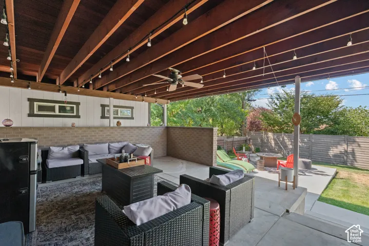 Covered patio with exposed wood-beam ceiling and recessed lighting opens to a level lawn and mature landscaping