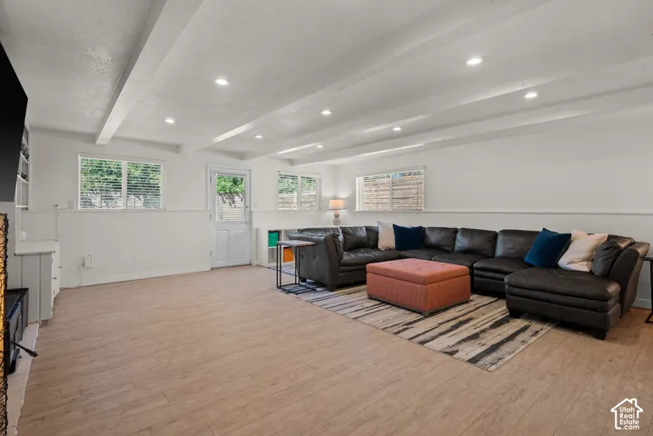 Spacious recreation room featuring coffered ceiling with recessed lighting, wood-finish flooring, and multiple windows providing natural light