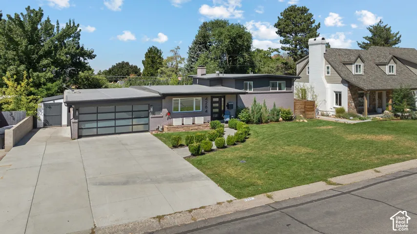 Modern residence featuring a sleek horizontal-panel garage door, concrete driveway with clean lines, and a contemporary dark-finish exterior with expansive windows