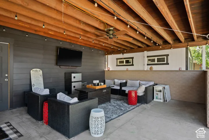 Covered patio featuring an exposed wood beam ceiling, string lighting, and a ceiling fan