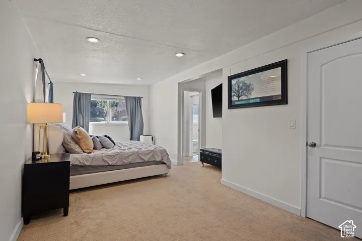 Recessed ceiling lighting, white walls, carpeted flooring, and a window with natural light
