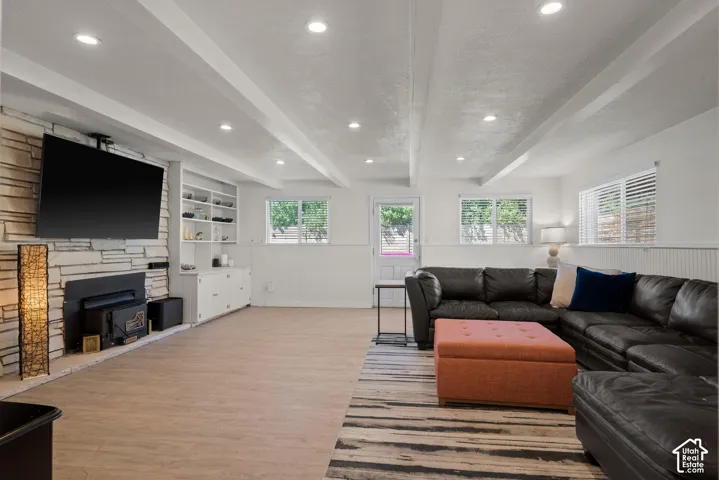 Stone-clad fireplace with a wood-burning insert, built-in shelving, wood-finish flooring, and recessed lighting