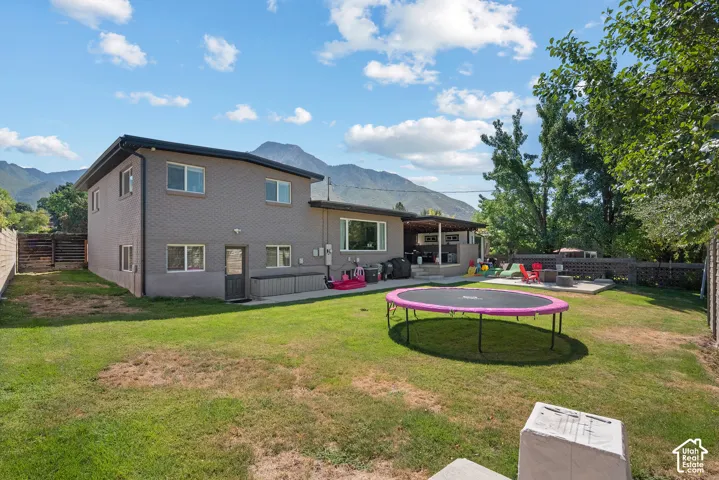 Expansive backyard featuring a manicured lawn, established trees, and a concrete patio