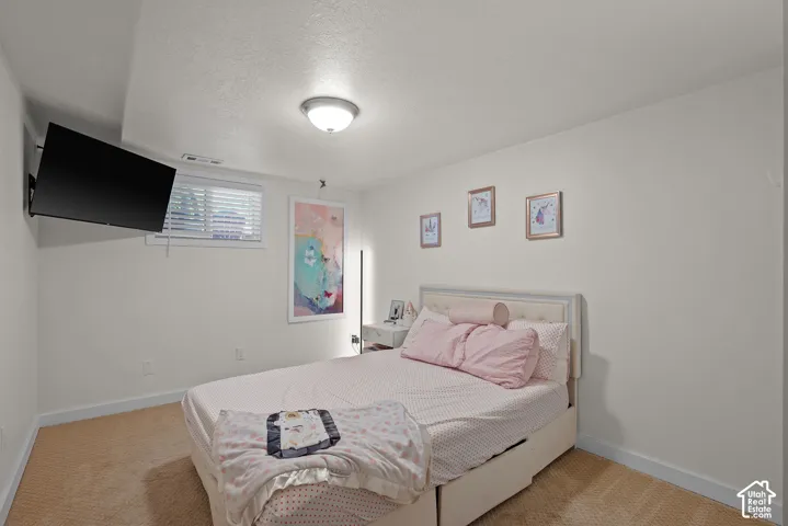 Bright secondary bedroom featuring neutral wall finishes, wood-finish flooring, and a ceiling-mounted light fixture