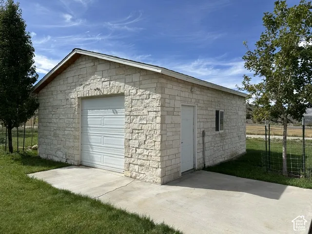 Stone exterior structure with a single garage door, an entry door, and a single window