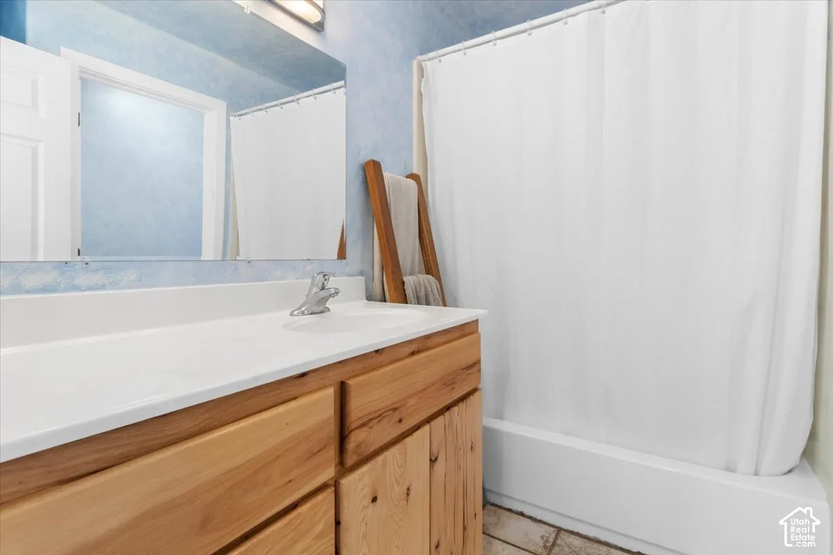 Full bathroom wood-finish cabinetry, integrated sink, and stainless steel faucet