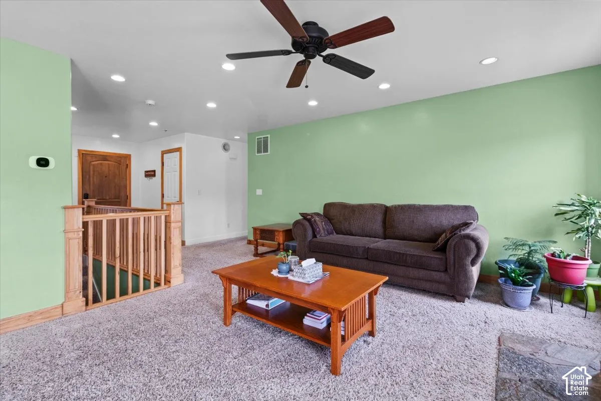 Recessed lighting, ceiling fan, wood-toned railing, and wood-paneled door