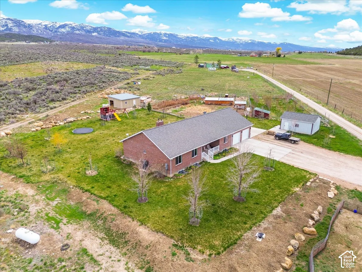 Brick exterior residence featuring a gray shingle roof, attached garage, work shop, fruit orchard, and large garden area.