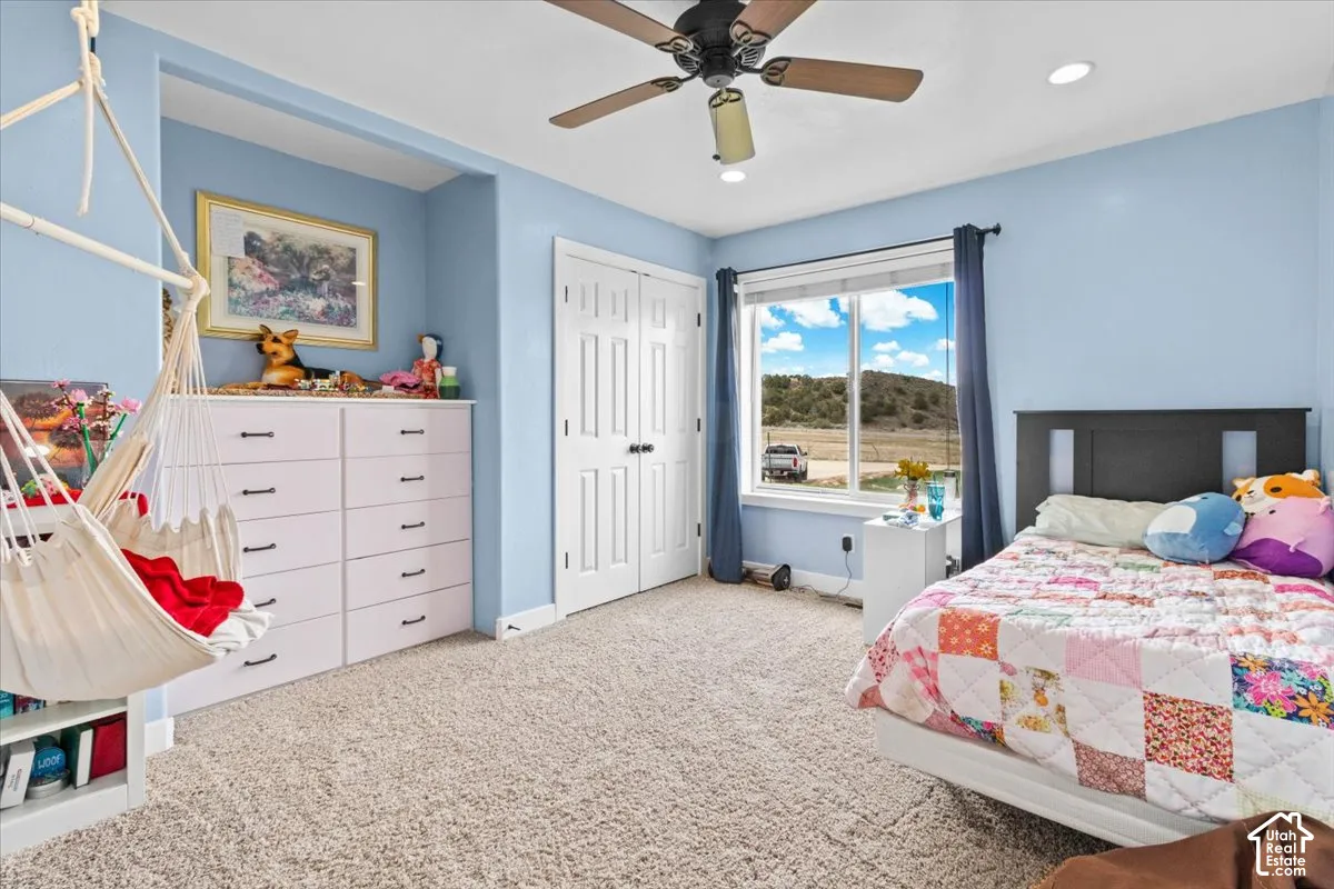 Recessed lighting, wood-finish ceiling fan, window with exterior scenery, carpeted flooring, and a built-in closet with double bifold doors