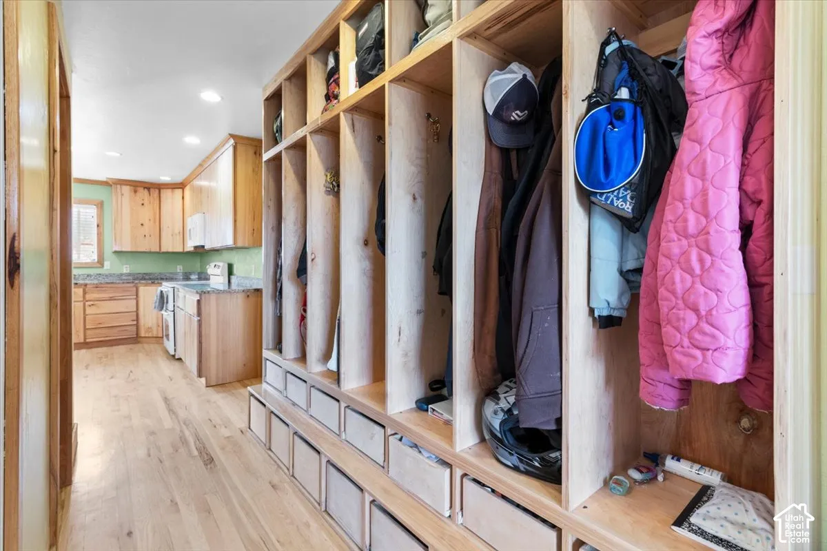 Built-in cubbies with integrated drawers, wood-finish flooring, recessed lighting, wood cabinetry, and a light green backsplash