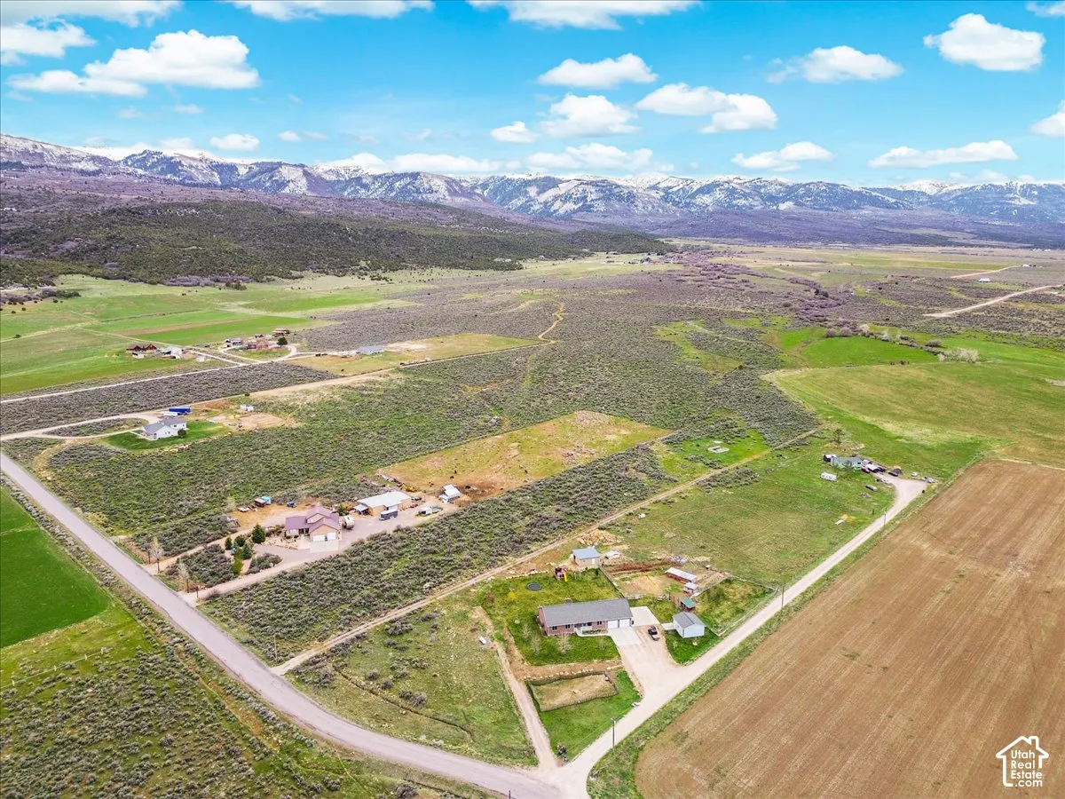 Expansive property featuring a gravel road, multiple structures, and agricultural land