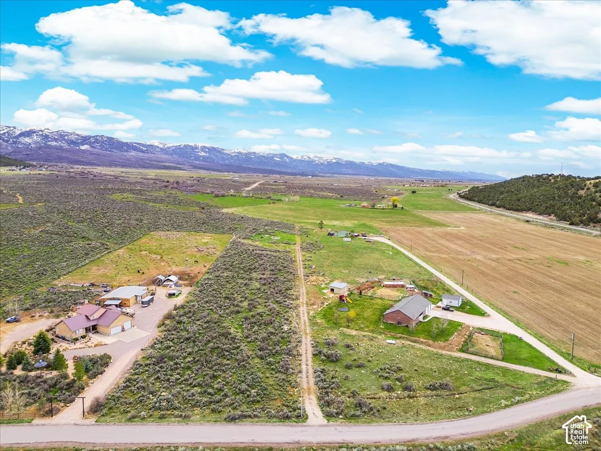 Expansive rural property featuring multiple structures, open fields, and mountain scenery