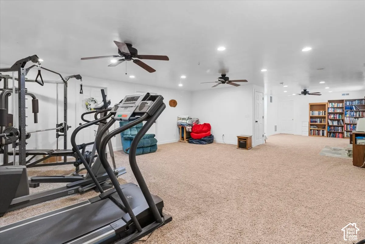 Expansive carpeted area with recessed lighting, multiple ceiling fans, and built-in shelving