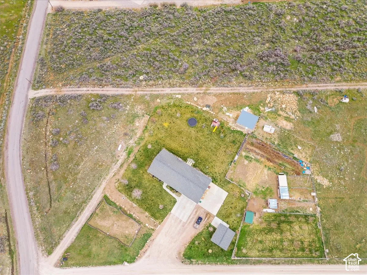 Expansive property featuring a central residence, gravel driveway, detached shed, and multiple fenced areas
