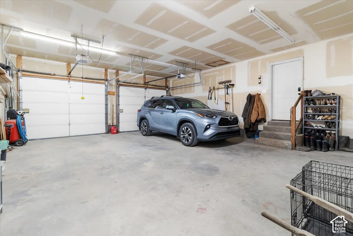 Large 2 door garage featuring automatic overhead doors and concrete flooring that has plenty of room for 3 cars and or extra storage.