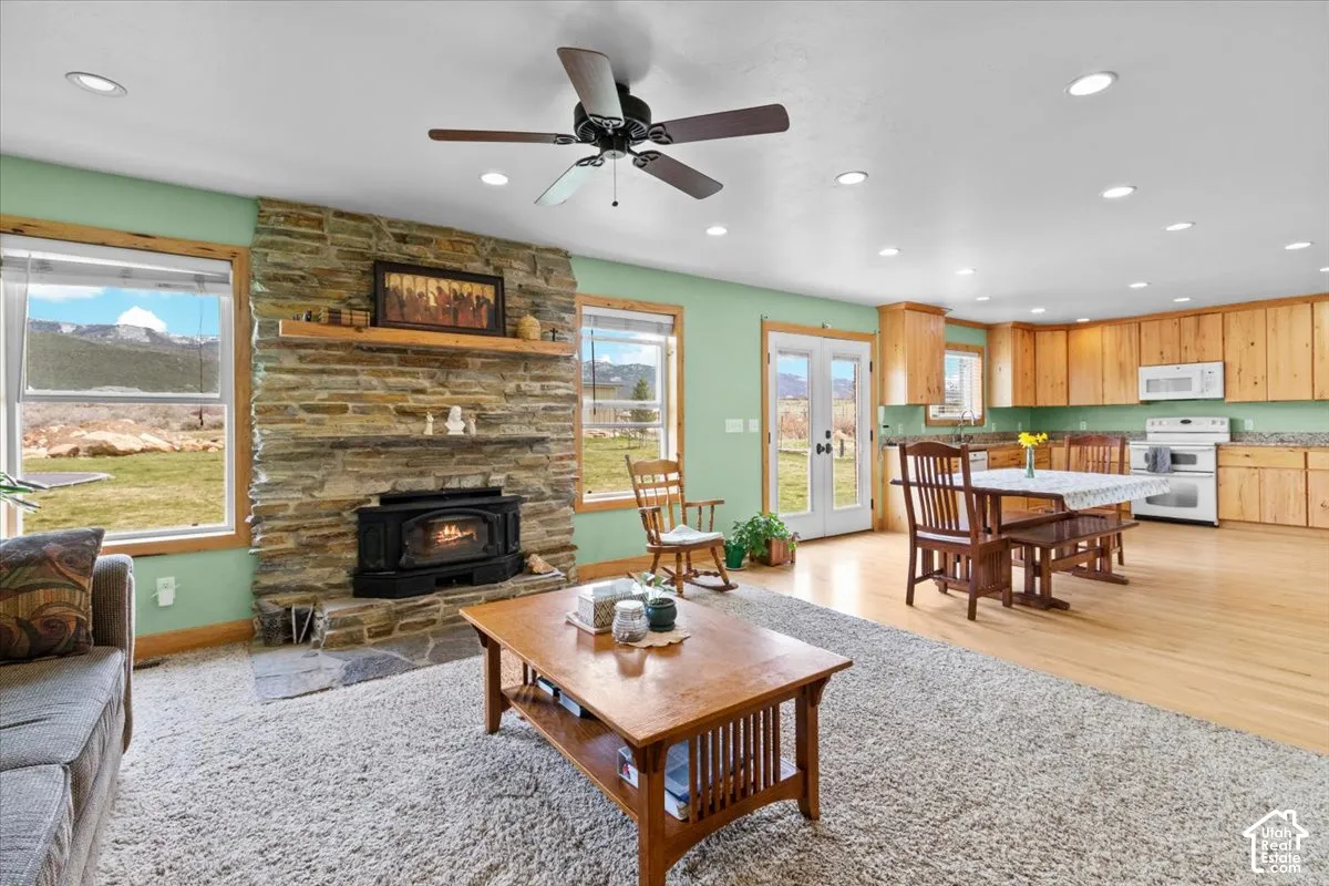 Open-concept living area featuring a stone-faced wood-burning fireplace, recessed lighting, and a ceiling fan