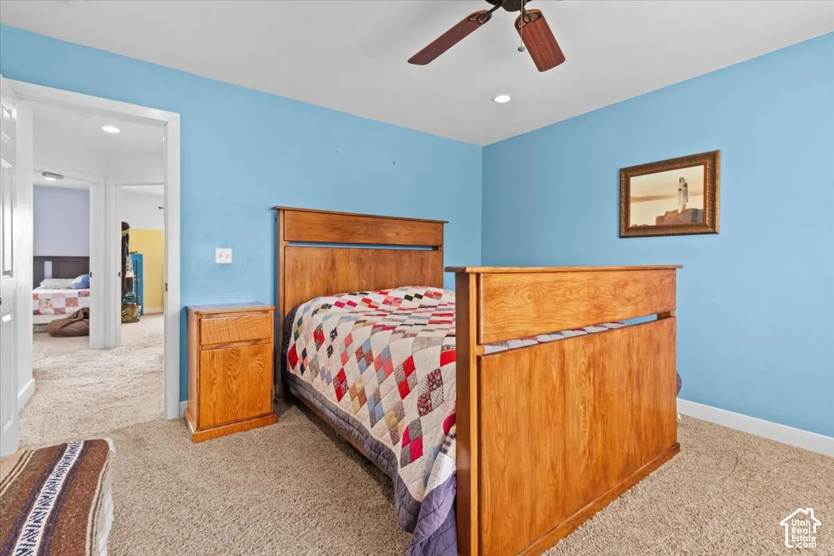 Carpeted bedroom with a ceiling fan, recessed lighting, and a wood-finish bed frame
