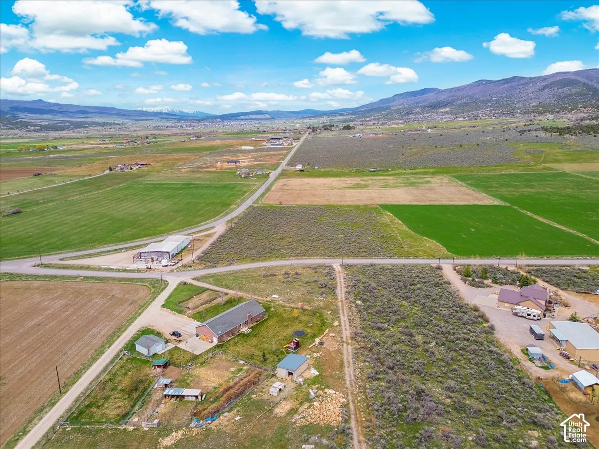 Expansive rural landscape featuring a mountainous backdrop, agricultural fields, and scattered residential properties