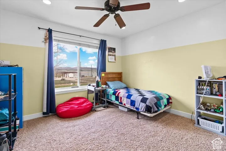 Recessed lighting, ceiling fan, large window, and light-colored carpeting