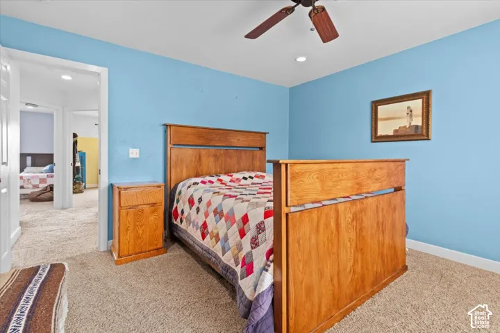 Carpeted bedroom with a ceiling fan, recessed lighting, and a wood-finish bed frame