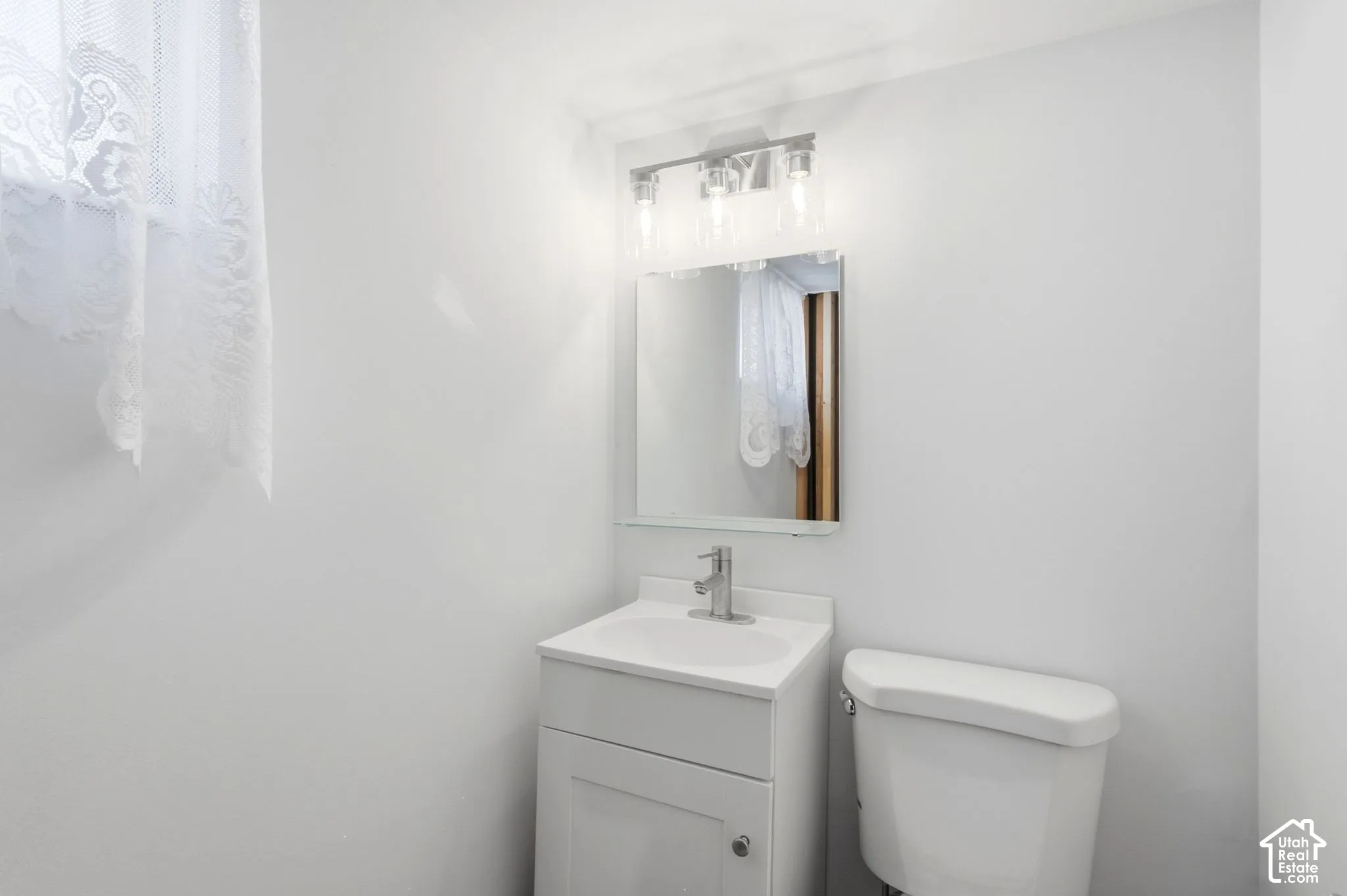 White vanity with integrated sink, chrome faucet, and rectangular mirror