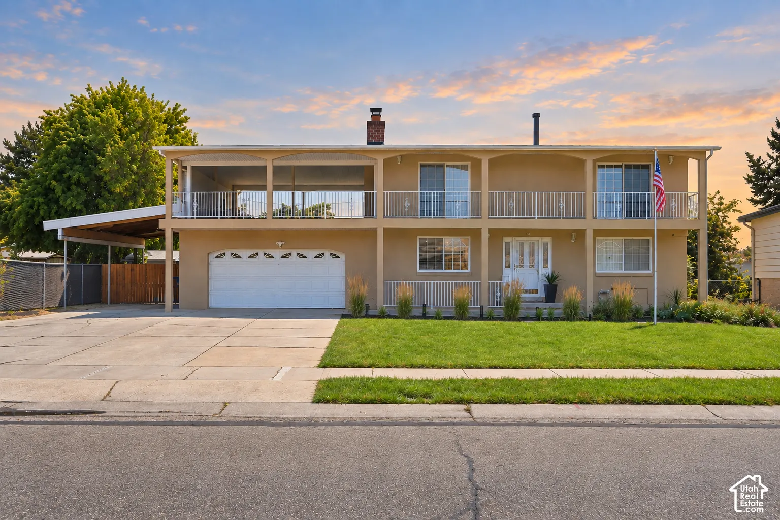 Two-story residence featuring a carport, integrated garage, and a full-width upper-level balcony with white railings