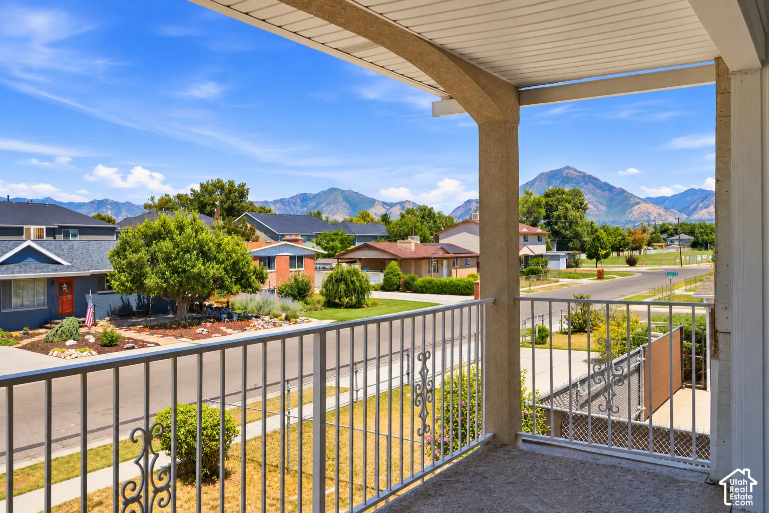 Covered balcony with decorative metal railing and distant mountain scenery