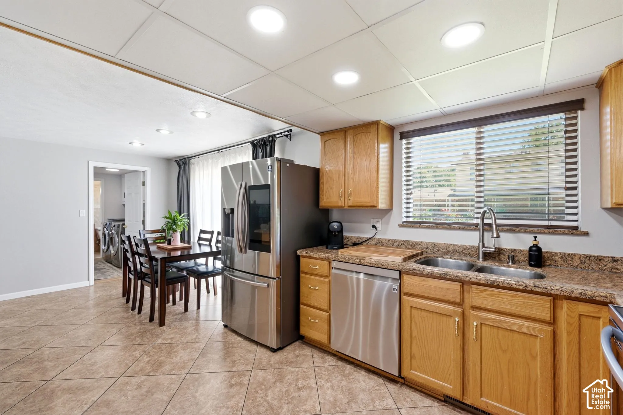 Kitchen featuring wood cabinetry, stainless steel appliances, a dual basin sink, and patterned countertops
