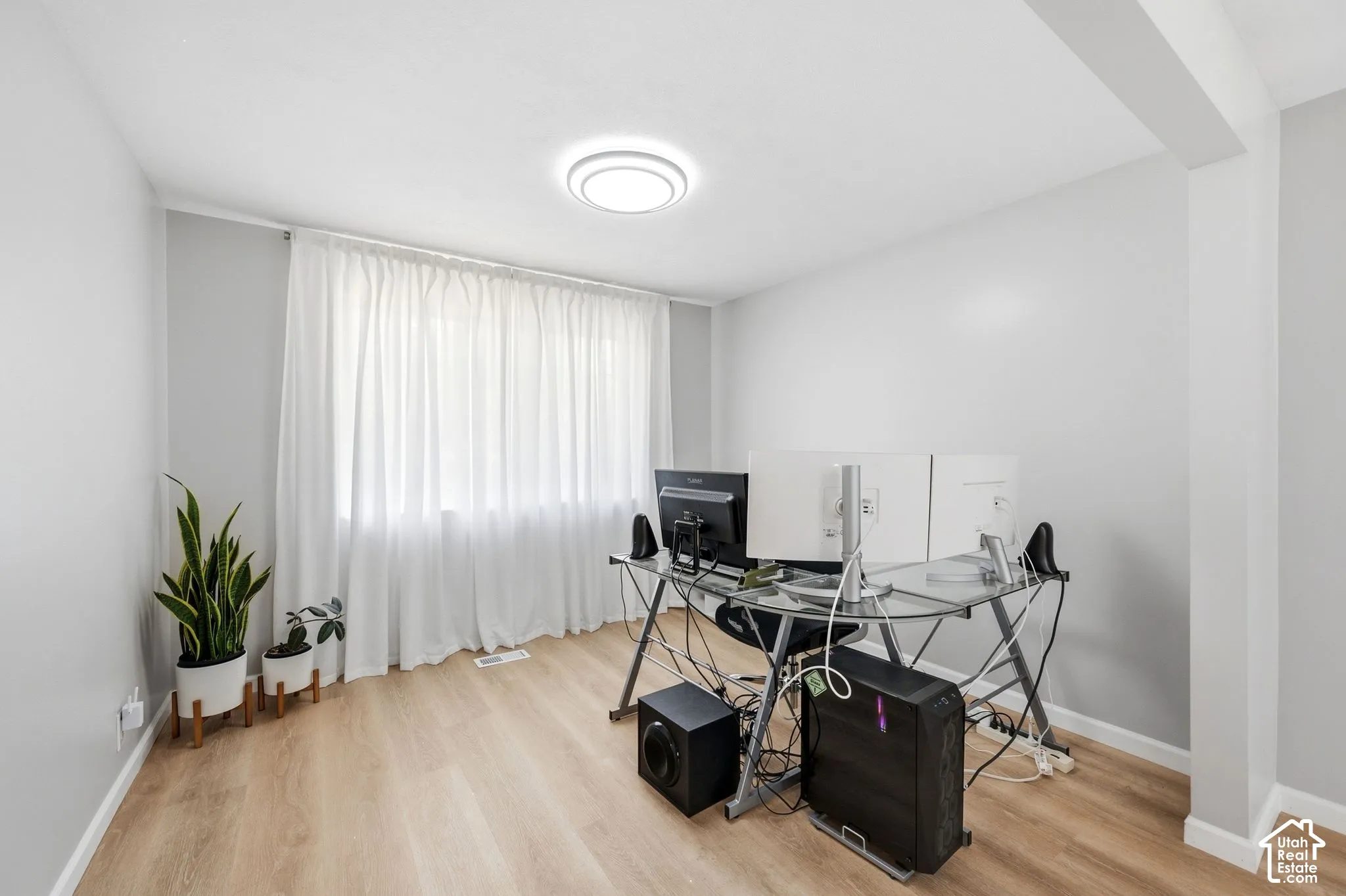 Light wood-finish flooring, recessed ceiling light, and a large window with privacy coverings