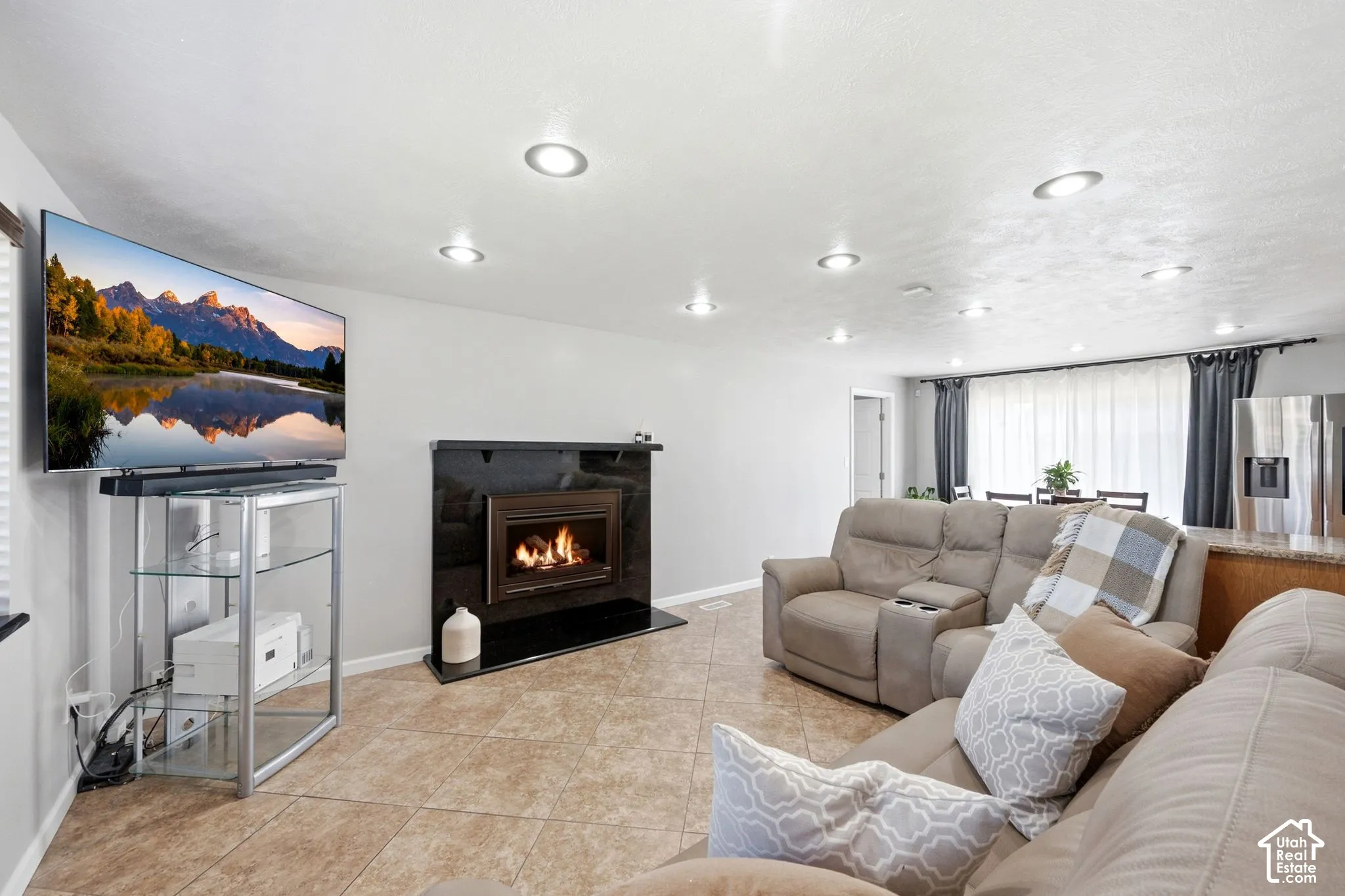 Recessed lighting and tile flooring complement the built-in fireplace with a black surround