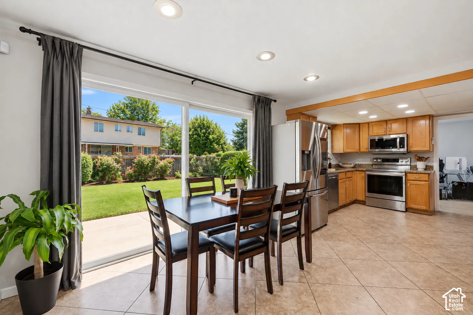 Open concept kitchen and dining area featuring tile flooring, oak cabinetry, stainless steel appliances, and sliding patio doors to an outdoor patio