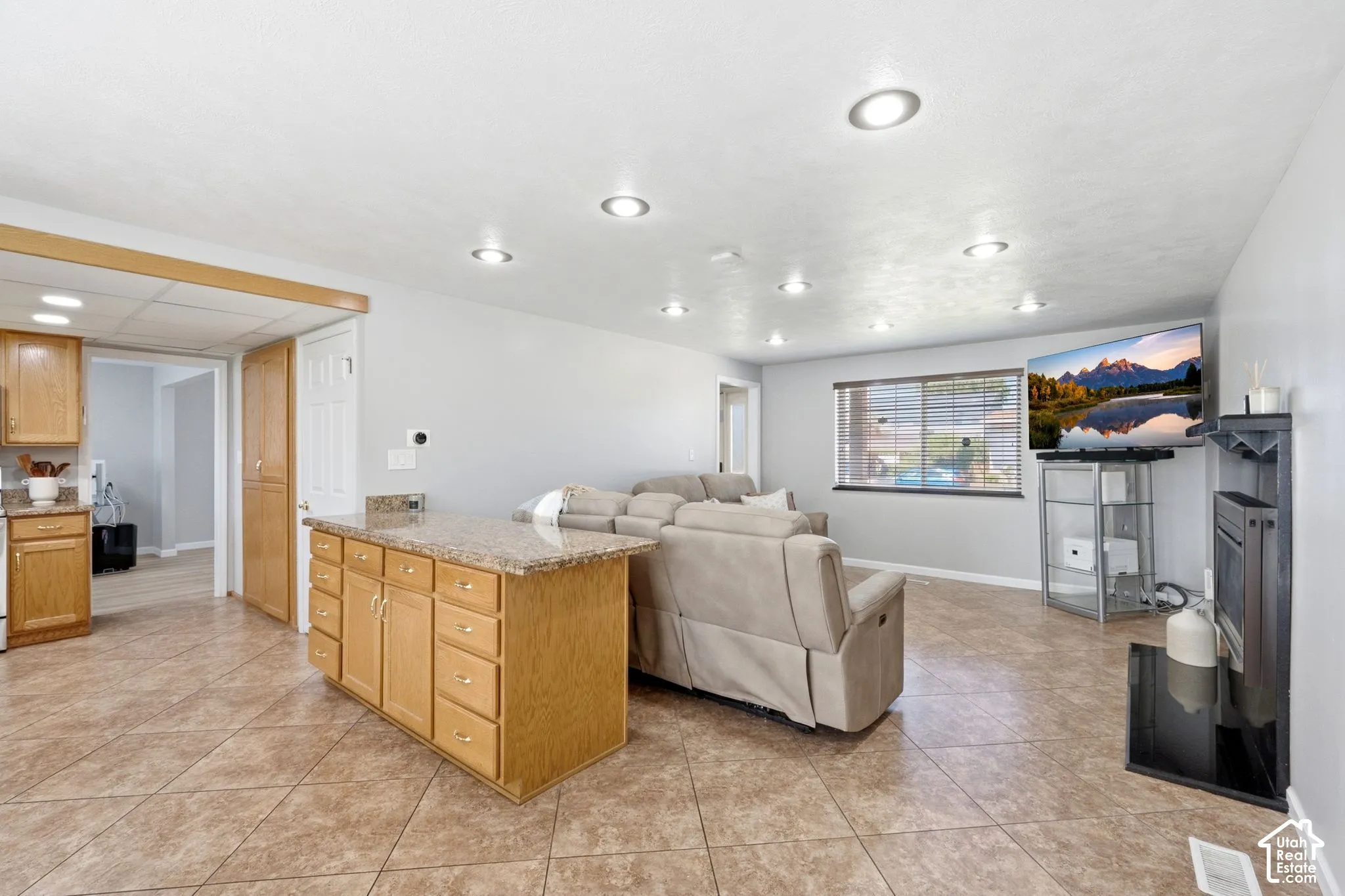 Recessed lighting throughout, tiled flooring, wood-finish cabinetry, and a built-in fireplace feature