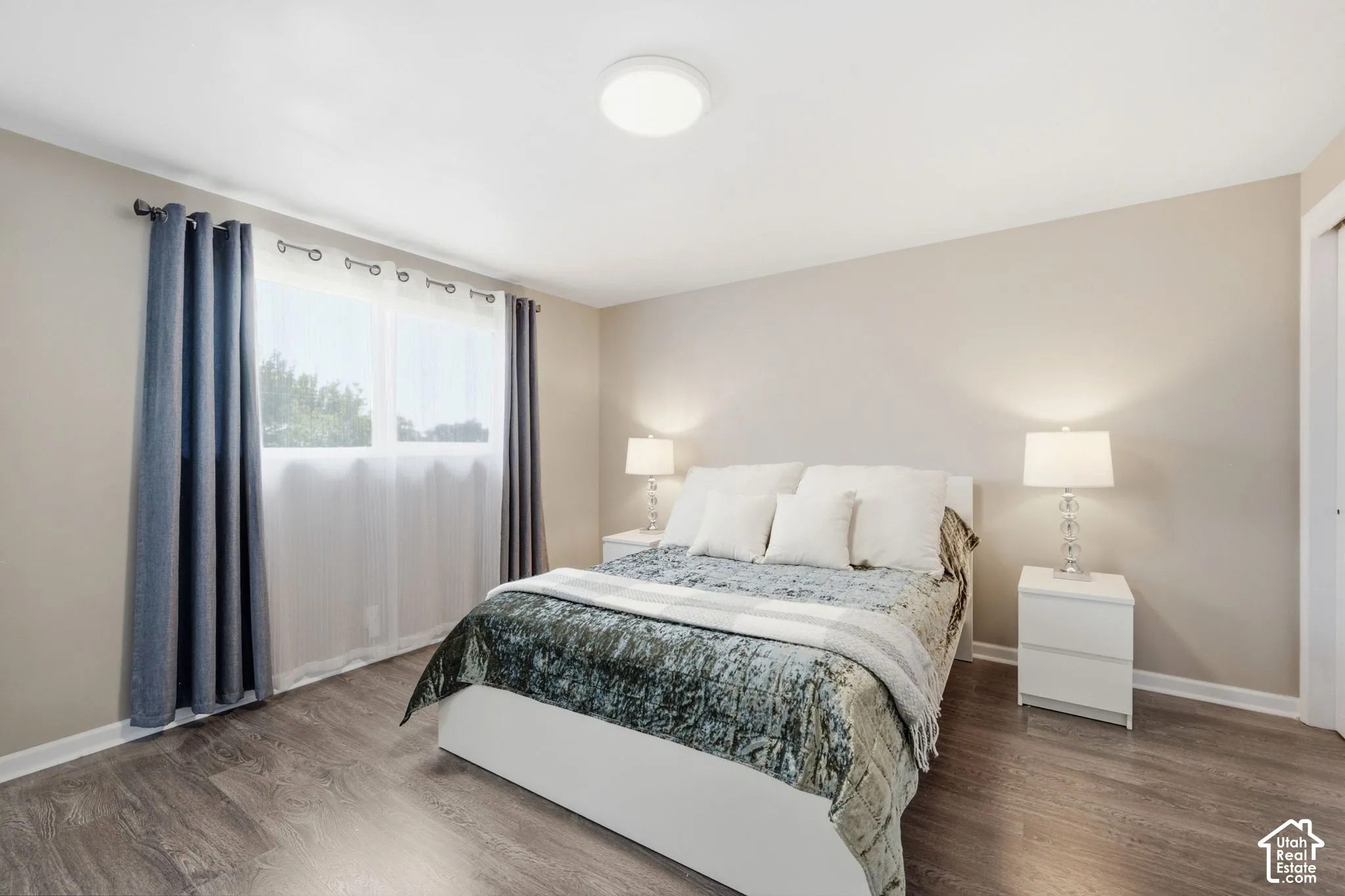 Neutral tone wall paint, wood-finish flooring, and a flush mount ceiling light fixture