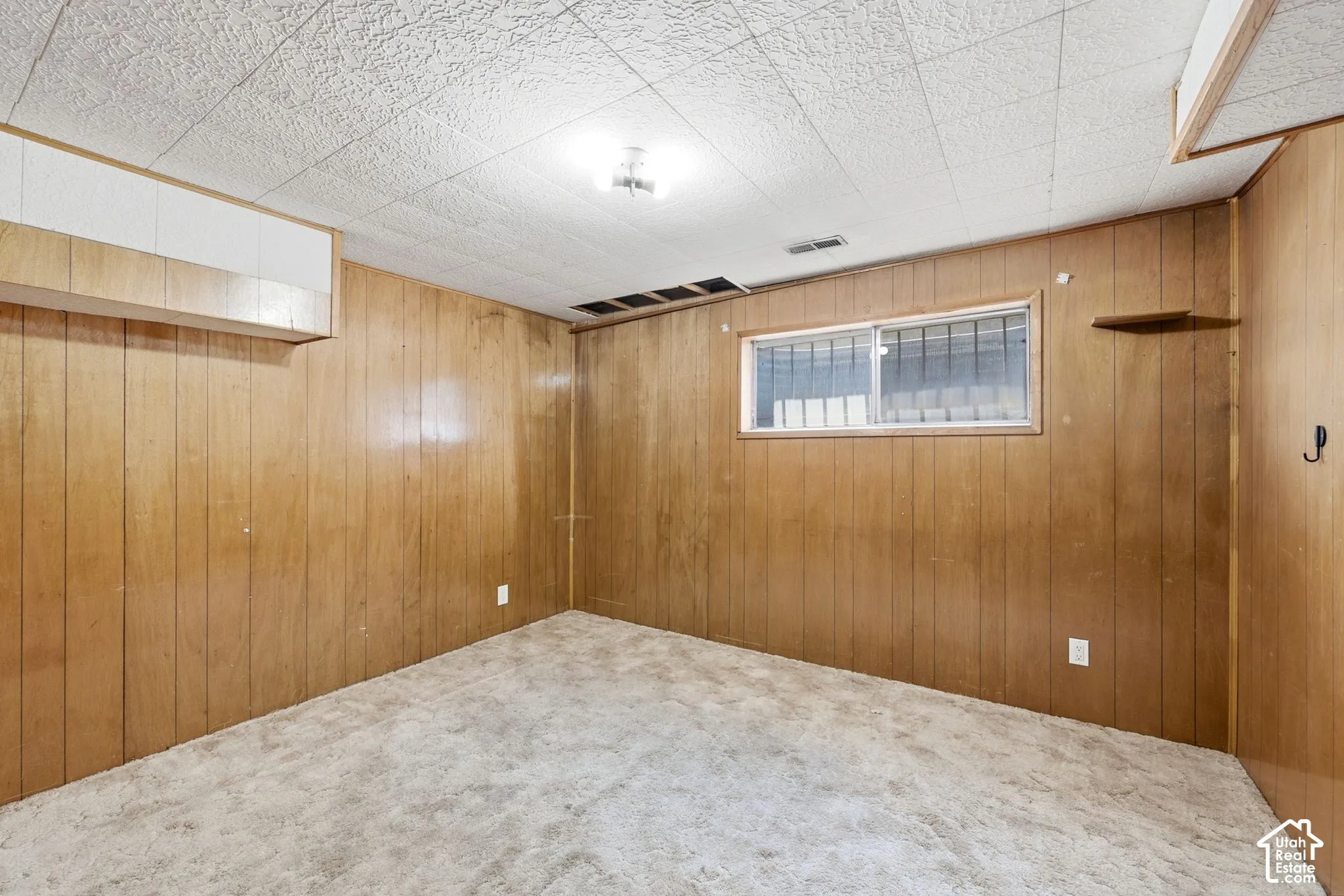 Wood-paneled walls with a window, textured ceiling, and flush-mount lighting