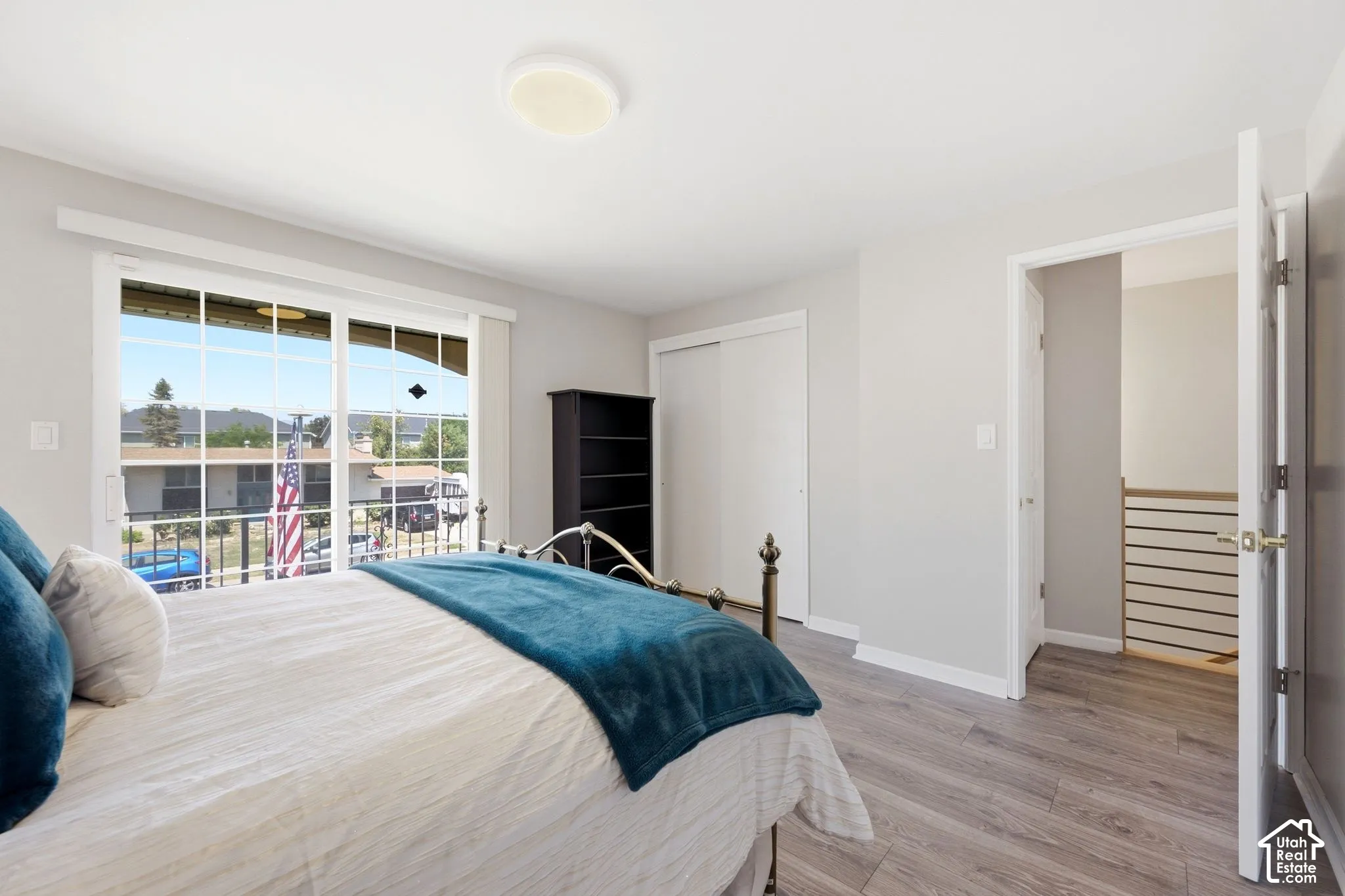 Sliding glass door, light wood-finish flooring, built-in closet with sliding doors, flush mount ceiling light, interior doorway