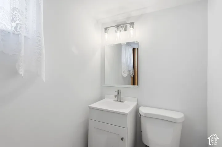 White vanity with integrated sink, chrome faucet, and rectangular mirror